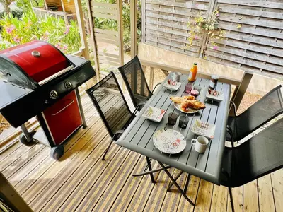 a picnic table with food and a grill on a deck at Chalet V tout confort proche des plages in Pianottoli-Caldarello