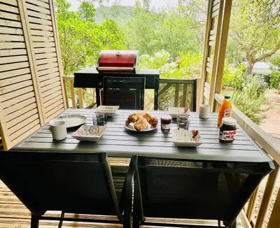a table with food and drinks on a porch at Chalet V tout confort proche des plages in Pianottoli-Caldarello
