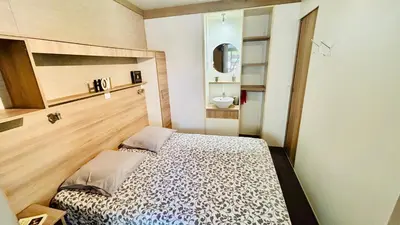 a small bedroom with a bed and a sink at Chalet V tout confort proche des plages in Pianottoli-Caldarello