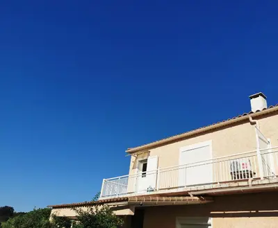 a building with a balcony and a blue sky at Appartement confort in Île de Diane