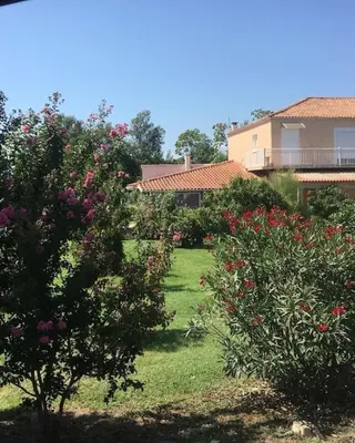 a garden with flowers and trees in front of a house at Appartement confort in Île de Diane