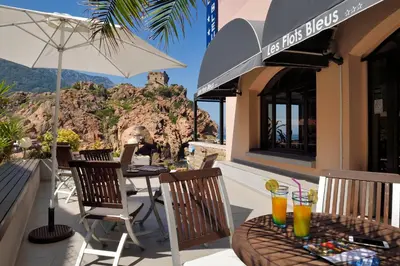 a restaurant with a table and chairs and an umbrella at Les Flots Bleus in Porto Ota
