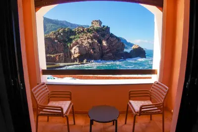 a window with a view of a rock in the ocean at Les Flots Bleus in Porto Ota