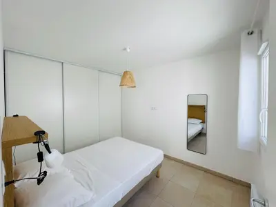 a white room with a bed and a mirror at Appt Lumineux pieds dans l'eau N181 in Linguizzetta