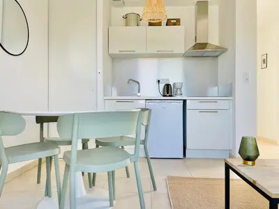 a kitchen with white cabinets and a table and chairs at Appt Lumineux pieds dans l'eau N181 in Linguizzetta