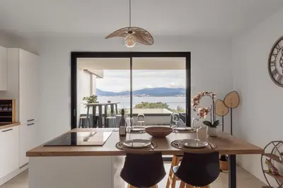 a kitchen with a dining table with a view of the ocean at Le Calypso B01 - Climatisé avec vue mer in Grosseto-Prugna
