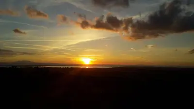 a sunset with the sun setting over the ocean at Appartements Luccisano in Borgo