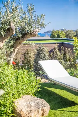 a white bench in a garden with a tree at Hôtel VILLA MAIER in Sainte-Lucie de Porto-Vecchio