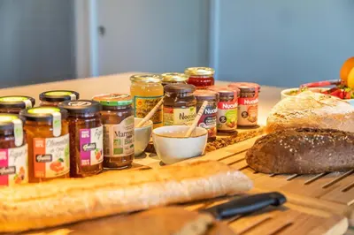 a table topped with lots of jars of peanut butter and bread at Hôtel VILLA MAIER in Sainte-Lucie de Porto-Vecchio