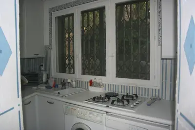 a kitchen with a stove and a sink and windows at Casetta indipendente con vista a Santa Giulia in Porto-Vecchio
