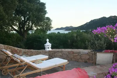 a couple of chairs and a table on a stone wall at Casetta indipendente con vista a Santa Giulia in Porto-Vecchio