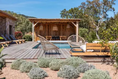 a backyard with a wooden deck with chairs and a pool at Villa Campemu Di Lecci in Lecci