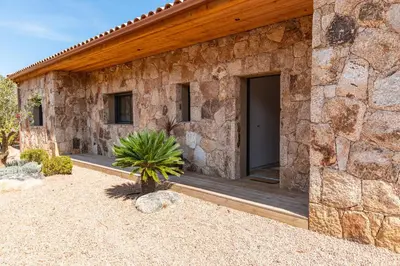 a stone house with a porch and a door at Villa Campemu Di Lecci in Lecci