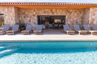 a patio with lounge chairs and a swimming pool at Villa Campemu Di Lecci in Lecci