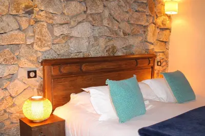 a bedroom with a bed with a stone wall at Bergerie du Prunelli in Cauro