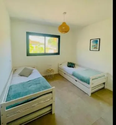 a bedroom with two beds and a window at Villa Lagon Bleu- Piscine privée- Corsu di Core in Favone