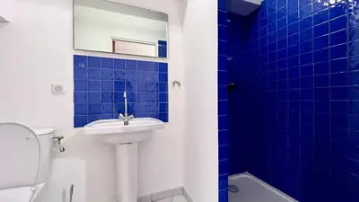 a blue tiled bathroom with a sink and a mirror at Coliving Ajaccio in Ajaccio