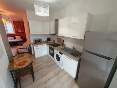 a kitchen with a refrigerator and a sink and a table at studio cosy idéalement situé parking privé in Ajaccio