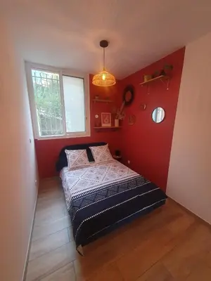 a bedroom with a bed in a red wall at studio cosy idéalement situé parking privé in Ajaccio