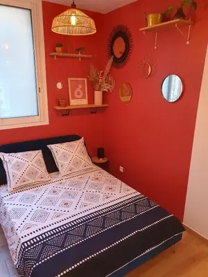 a bedroom with a bed with a red wall at studio cosy idéalement situé parking privé in Ajaccio