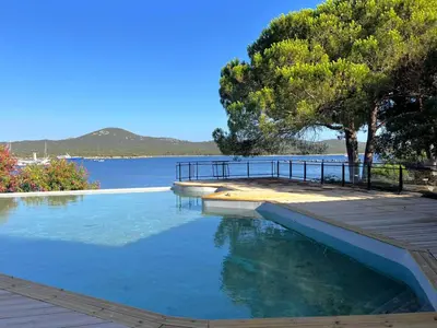 a balcony with two chairs and a backpack at APPT T3 terrasse dans résidence bord de mer avec piscine in Pianottoli-Caldarello