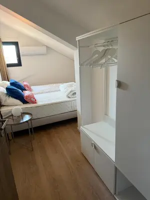 a small white bedroom with a bed and a desk at APPT T3 terrasse dans résidence bord de mer avec piscine in Pianottoli-Caldarello