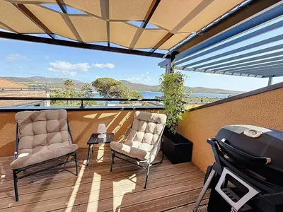 a patio with two chairs and a grill on a deck at APPT T3 terrasse dans résidence bord de mer avec piscine in Pianottoli-Caldarello
