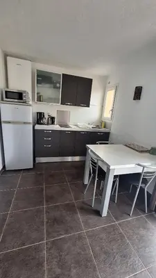 a kitchen with a white table and a white refrigerator at Résidence Dolce Vita in Propriano