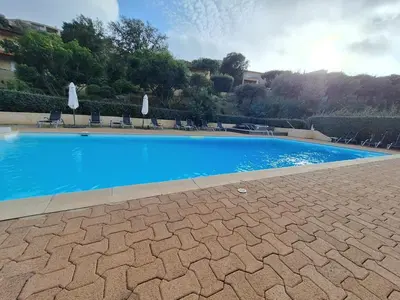 a large blue swimming pool with chairs and umbrellas at Résidence Dolce Vita in Propriano