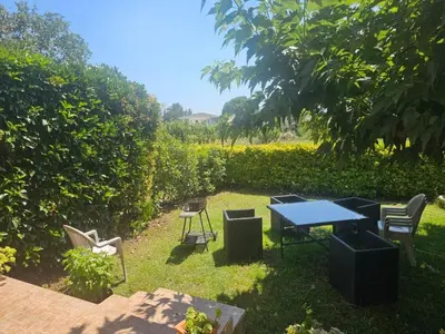 a patio with a table and chairs in the grass at Rez de villa in Borgo