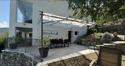a white house with a patio with a table and chairs at Appartement en Corse in Noceta