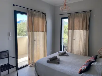 a bedroom with a bed and a large window at T3 Tout confort à 5 mn des plages de Pinarello in Pinarellu