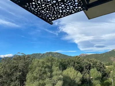 a view of the mountains from under a umbrella at T3 Tout confort à 5 mn des plages de Pinarello in Pinarellu