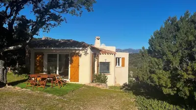 a house with a table and chairs in front of it at Villa Porra 100m2, pleine nature, piscine, vue mer in Porto-Vecchio