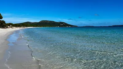 a beach with blue water and mountains in the background at Villa Porra 100m2, pleine nature, piscine, vue mer in Porto-Vecchio