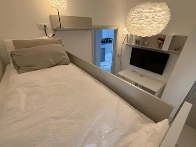a small bedroom with a bed and a flat screen tv at Appartement de luxe type 4 Eden Suite Sanguinaires vue mer avec piscine chauffée résidence Ajaccio in Ajaccio