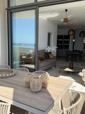 a dining room table with chairs and a living room at Appartement de luxe type 4 Eden Suite Sanguinaires vue mer avec piscine chauffée résidence Ajaccio in Ajaccio