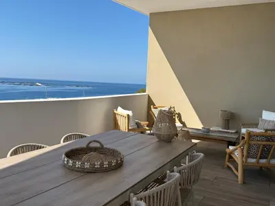 a table on a balcony with a view of the ocean at Appartement de luxe type 4 Eden Suite Sanguinaires vue mer avec piscine chauffée résidence Ajaccio in Ajaccio