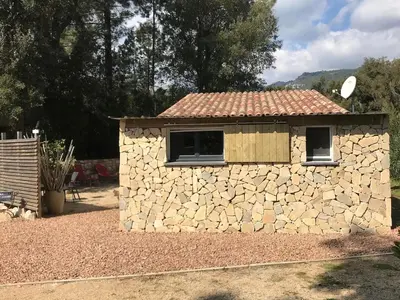 a building with a stone wall and two windows at L'Attellu Di Babbu pour 2 in Lecci