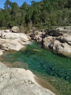 a river with clear blue water and rocks at L'Attellu Di Babbu pour 2 in Lecci