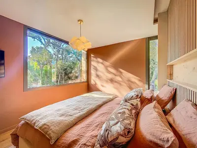 a bedroom with a bed with a large window at Villa L'Immortelle in Lecci