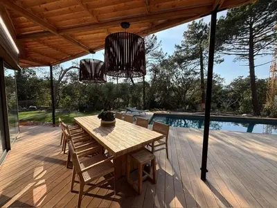 a wooden table and chairs on a deck with a pool at Villa L'Immortelle in Lecci
