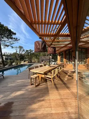 a wooden table and benches on a patio with a pool at Villa L'Immortelle in Lecci