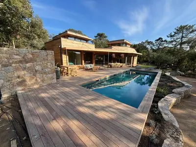 a house with a swimming pool and a wooden deck at Villa L'Immortelle in Lecci