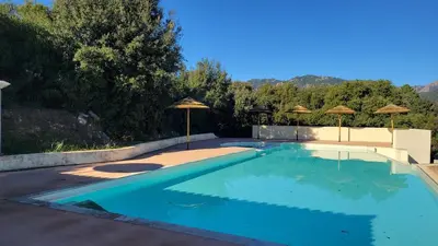 a swimming pool with umbrellas and a swimming pool at Villa Résidence San Martinu Sainte Lucie De Porto Vecchio in Zonza