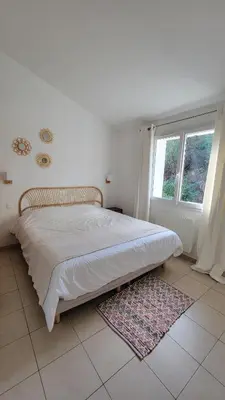 a bed in a bedroom with a window and a rug at Villa Résidence San Martinu Sainte Lucie De Porto Vecchio in Zonza