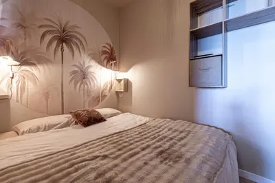a bedroom with a large bed with a palm tree wallpaper at Le Yucca - Vue mer 100 m de la plage in Pietrosella
