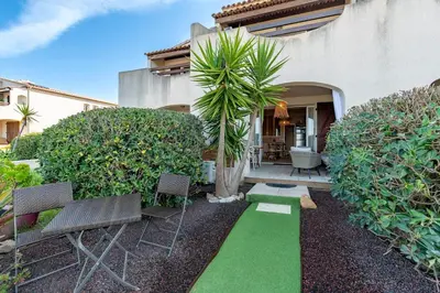 a yard with chairs and a green lawn at Le Yucca - Vue mer 100 m de la plage in Pietrosella