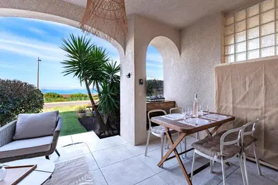 a dining room with a table and chairs on a patio at Le Yucca - Vue mer 100 m de la plage in Pietrosella