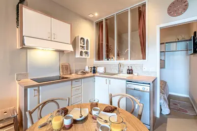 a kitchen with a wooden table with chairs and a sink at Le Yucca - Vue mer 100 m de la plage in Pietrosella